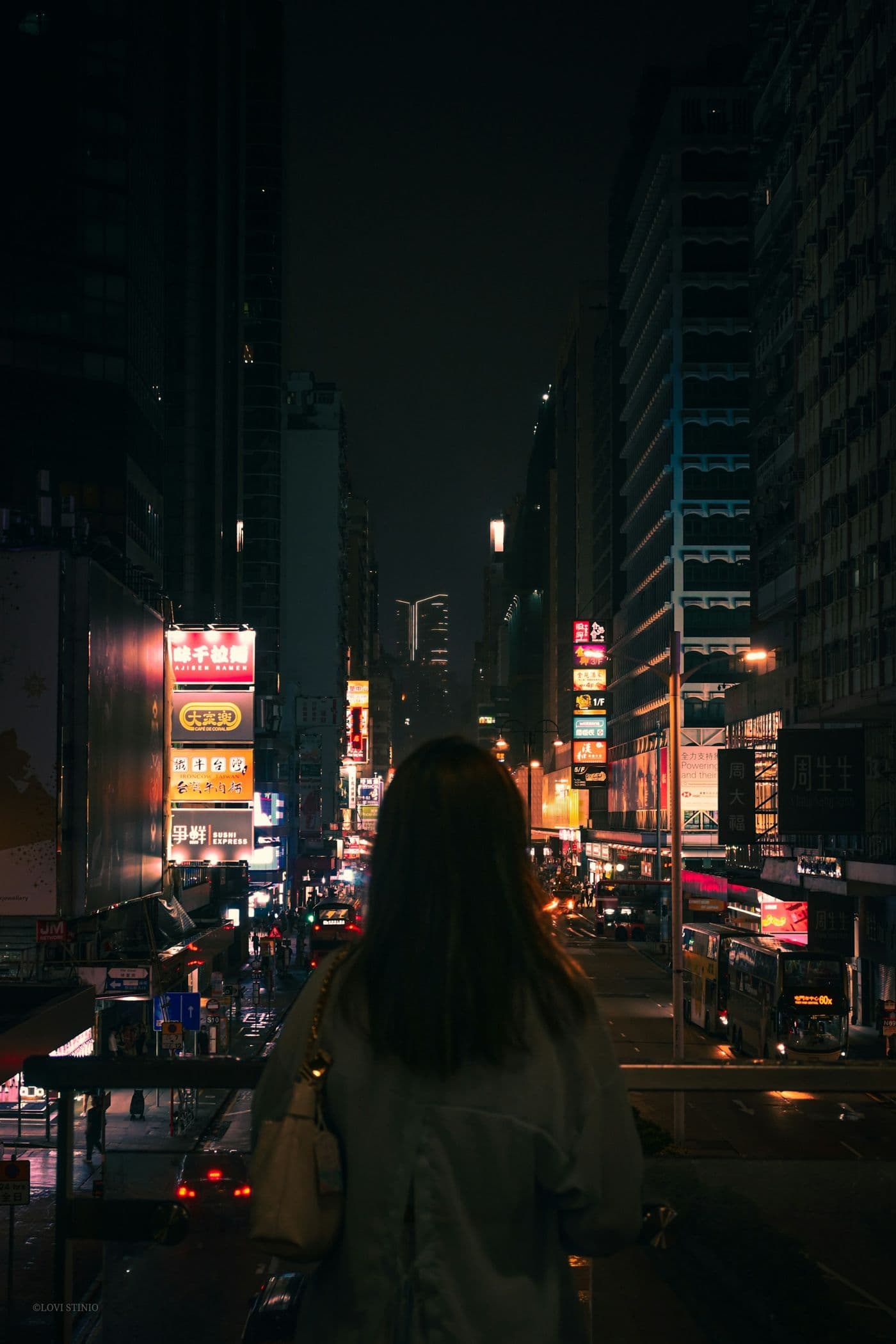A woman walking down a neon-lit city street at night