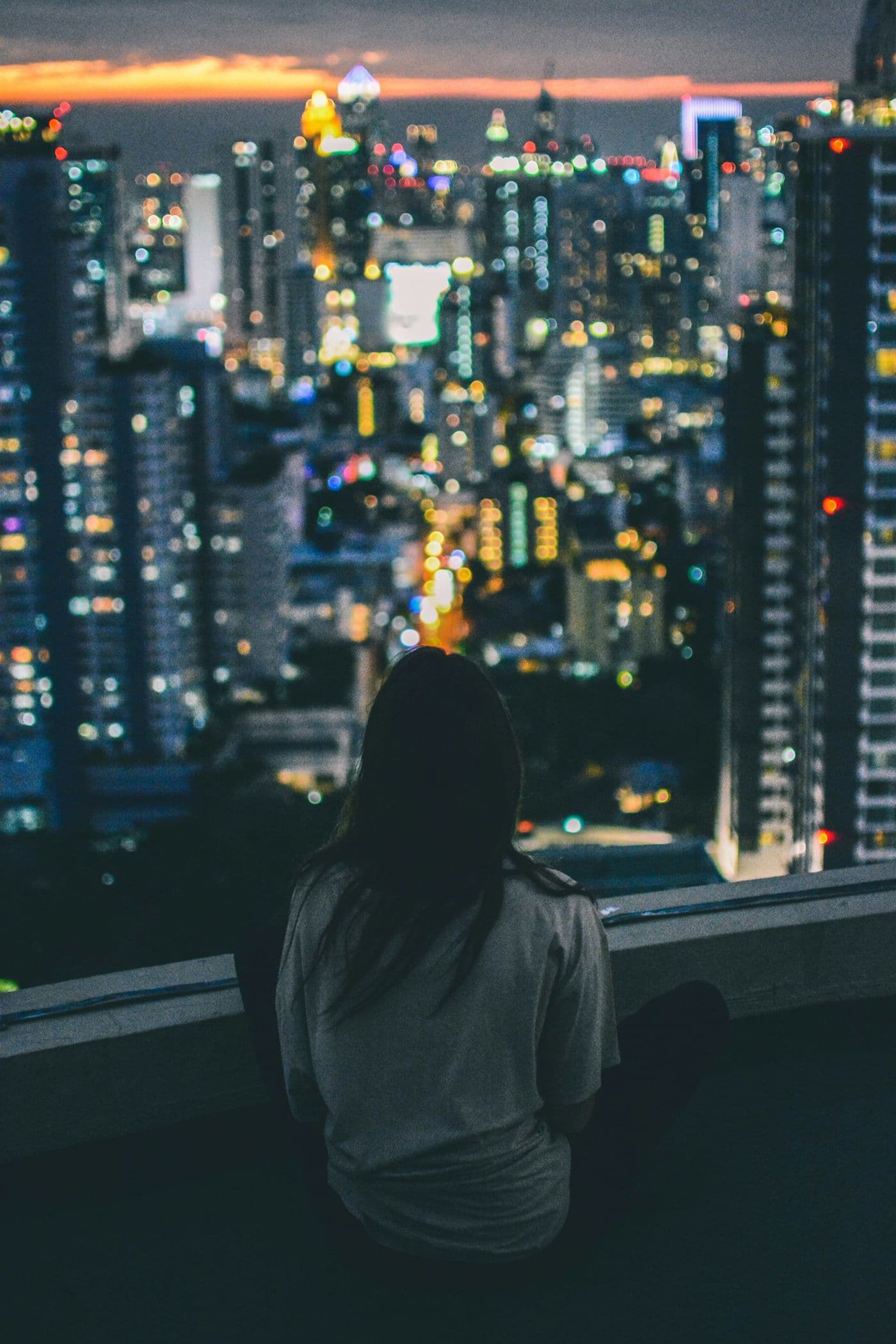 A woman looking out over the city skyline at night
