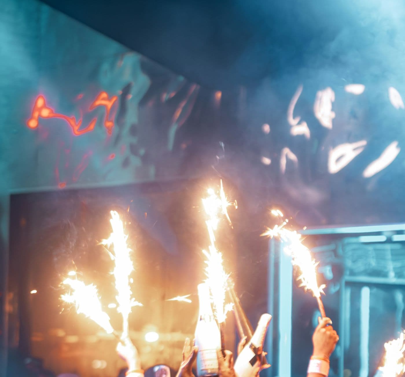 Sparklers held up over champagne bottles at a club
