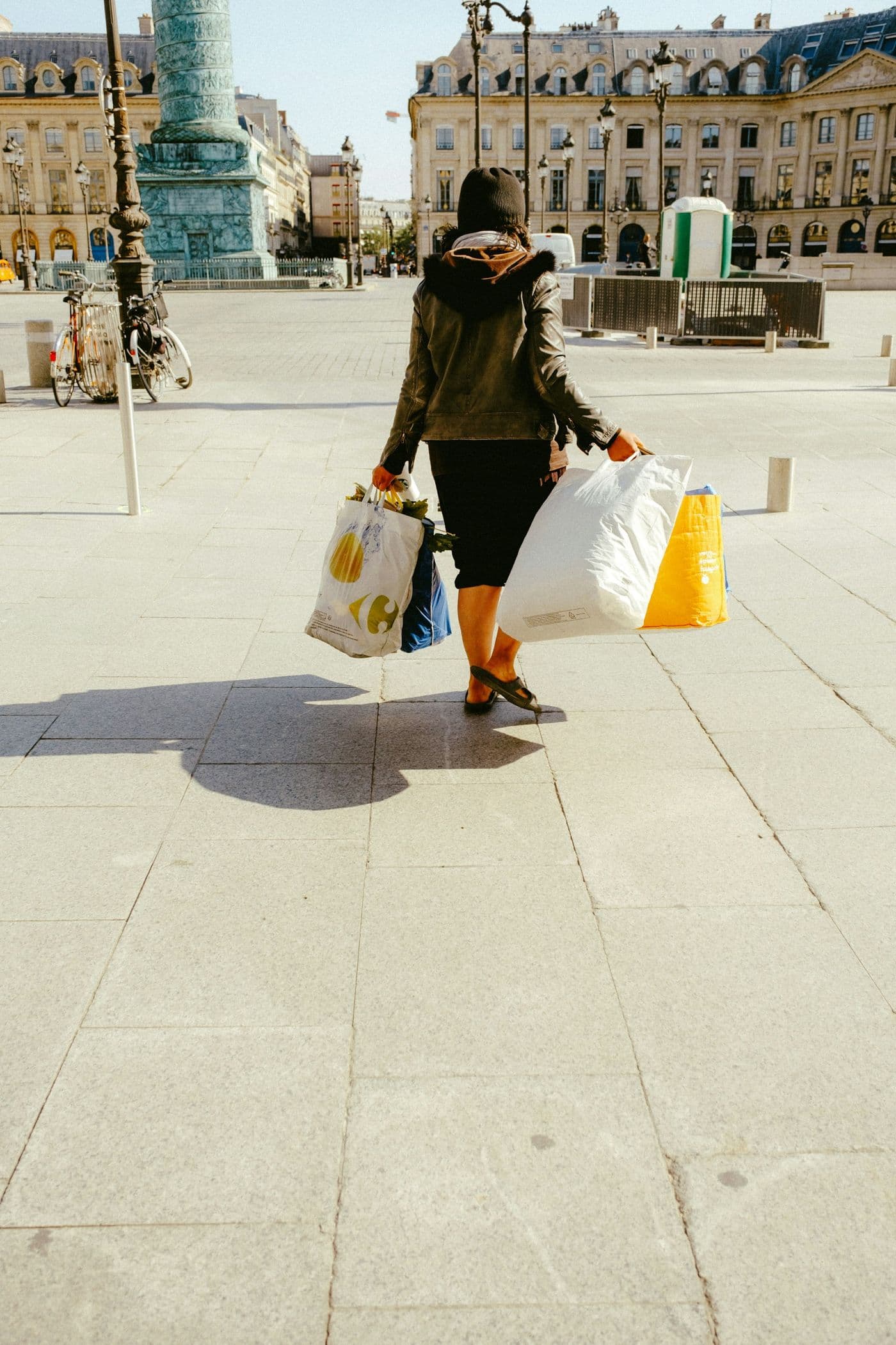 A woman carrying shopping bags across a Paris square